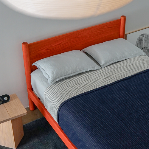 Custom Color modern solid oak designer bed frame Keeps Architect bed with headboard integrated joinery in bright red vermillion with navy duvet and blue sheets with Keeps Nightstand in light natural finish and alarm clock