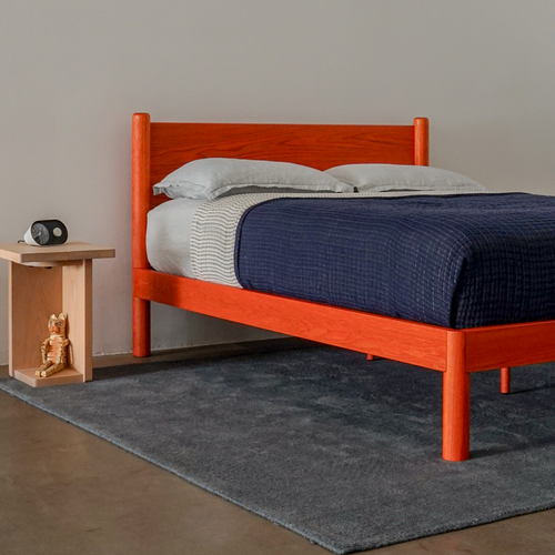 Custom Color modern solid oak designer bed frame Keeps Architect bed with headboard integrated joinery in bright red vermillion with navy duvet and blue sheets with Keeps Nightstand in light natural finish and alarm clock