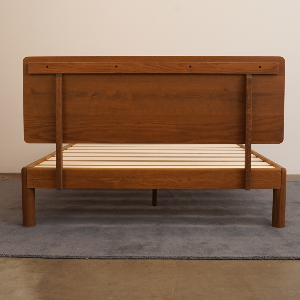 Rear assembly view of Keeps solid oak bed frame and attached wood headboard with bolted joinery in acorn brown finish