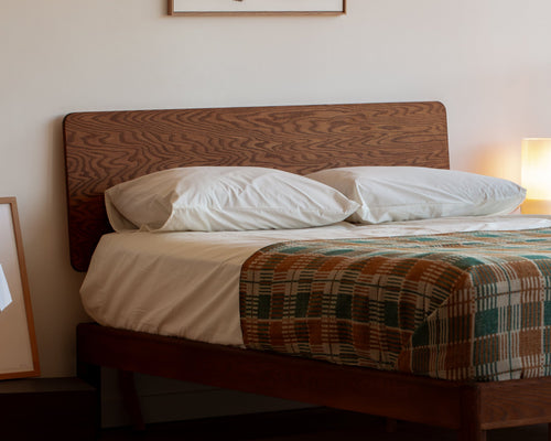Keeps home bolted queen bed frame with standalone headboard in acorn finish with mattress and sheets in bedroom
