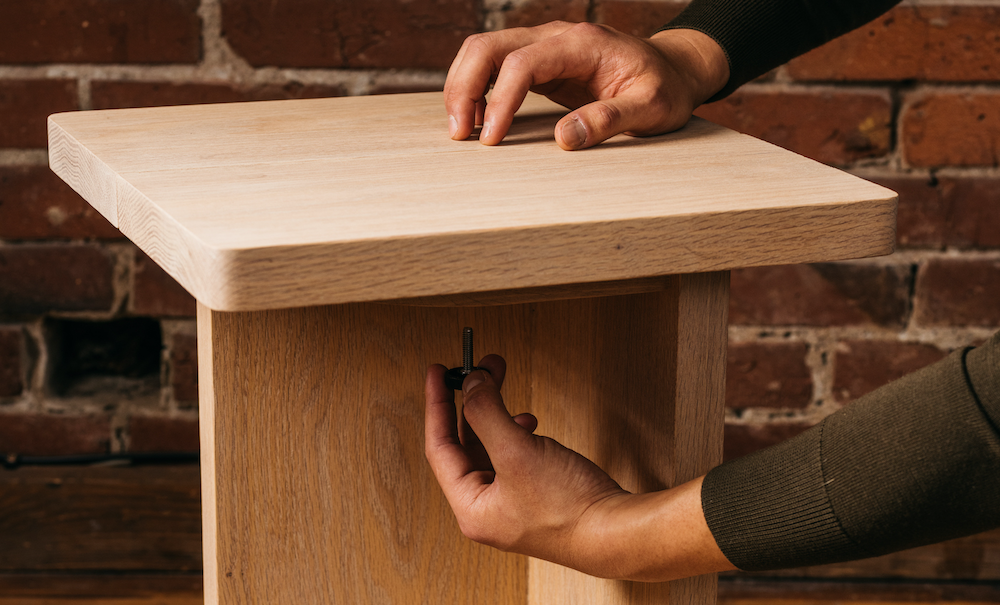 Person assembling Keeps Oak Nightstand with adjustable easy assembly screws