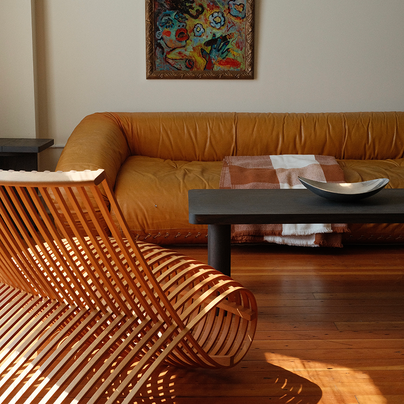 Another Furniture Store studio dispaly of vintage mustard sofa, weaved wood design chair, and Keeps smoked long coffee table